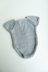 Various colors and types of cotton clothing, knitted newborn clothes and newborn hats on a white background.