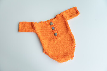 Various colors and types of cotton clothing, knitted newborn clothes and newborn hats on a white background.