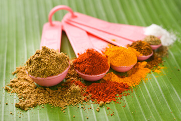 Indian spices powder in spoon, banana leaf background. Organic Indian spicy curry masala for making curry in India. Curry powder mix. biryani masala. garam masala for Indian curry turmeric, red chilli