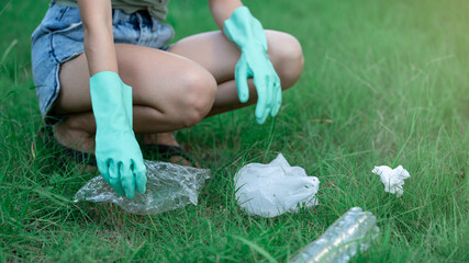 Woman hand keeping plastic waste into black bag at park, dirty waste in her hands.