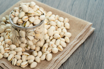 Pistachio nuts in transparent glass jar on a wooden table. Healthy food high protein.