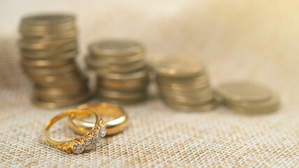 Obraz na płótnie Canvas Wedding rings with stack of coins, saving money for marry.