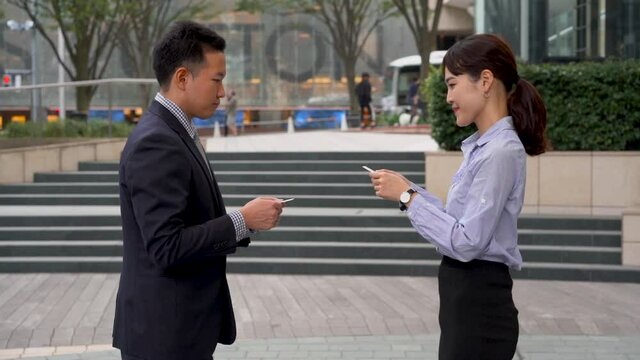 Japaneses man and woman greet each other with bow and exchange business cards. Respect and formality.