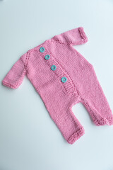 Various colors and types of cotton clothing, knitted newborn clothes and newborn hats on a white background.