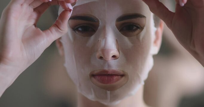 Portrait of a beautiful woman, paper sheet masks on face, female slowly removes a beauty mask from her face, skin care.