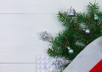 Celebrating Christmas in the healthcare industry. Top view of flat lay. Christmas hat with tree branches, decorations and pills