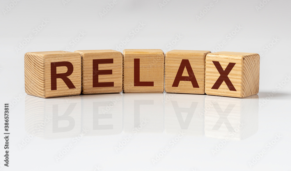 Fototapete relax word written on wooden cube blocks on white glossy table with reflection