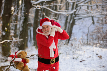 Santa Claus coming to the winter forest with a bag of gifts, snow landscape. Merry Christmas and happy new year. Santa with present on Christmas Eve.