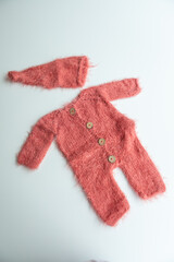 Various colors and types of cotton clothing, knitted newborn clothes and newborn hats on a white background.