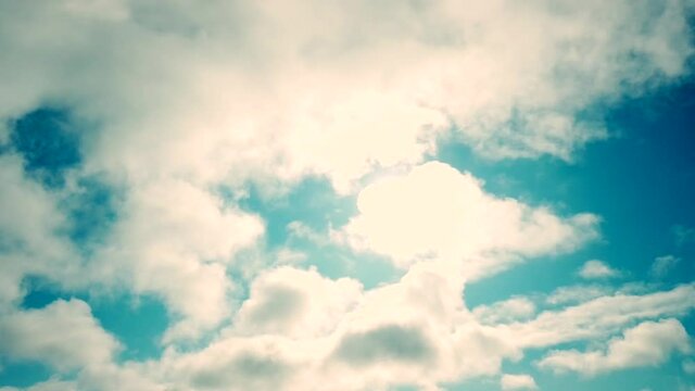 Slow-moving majestic clouds with sun behind and blue sky