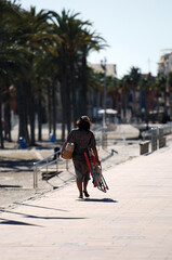 A young woman carries her beach supplies to her car.