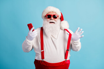 Fototapeta na wymiar Portrait of his he nice attractive cheerful cheery white-haired Santa using device 5g app social network blogging shop order sale having fun isolated bright vivid shine vibrant blue color background