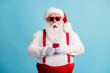 Portrait of his he nice attractive amazed stunned white-haired Santa using device 5g app browsing media multimedia blogging shop order sale isolated bright vivid shine vibrant blue color background