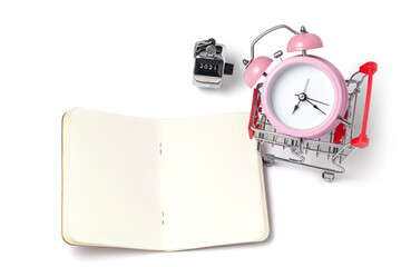 alarm clock in a pink plastic case and black hands in a metal shopping cart with tally click counter on a white background selective focus isolated
