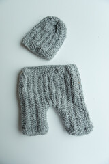 Various colors and types of cotton clothing, knitted newborn clothes and newborn hats on a white background.