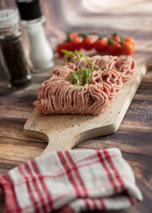 
Raw minced meat on a board with tomatoes.