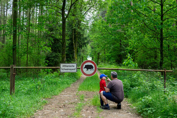 Father and son are standing in the forest on a path that is closed with a barrier.