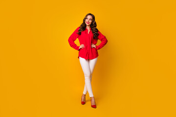 Full body photo of chic business lady hold hands sides look wondered empty space toothy smiling wear red office shirt white pants high-heels isolated yellow bright color background