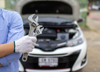 Fototapeta na wymiar Car repair service, the hand of a car mechanic holding a wrench preparing to repair cars entering the garage.