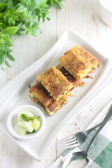 Martabak telur, Indonesian traditional savoury food made from egg, meat, and some spices. White plate and background.


