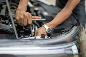 Automobile mechanic repairman hands repairing a car engine automotive workshop with a wrench, car service and maintenance.
