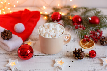 Obraz na płótnie Canvas Christmas background, coffee mug and marshmallows , red Christmas toys, glowing lights . Merry Christmas greeting card