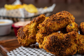 Baked chicken wings with sesame and sauce on wooden background