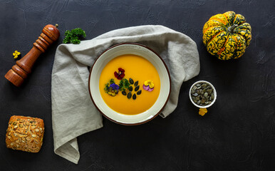 Autumn pumpkin cream soup with edible flowers