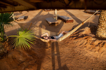 Happy girl relaxing on beach hammock in tropical vacation resort hotel. Holidays in the tanning...