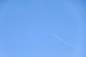 flying plane left a white trail on the blue sky