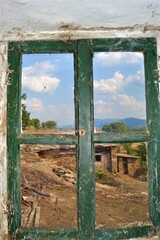 Fototapeta premium Bulgaria and views from cute and small villages during bright day.Vintage window and dirty glass seen outside of small village view. 