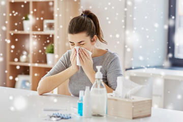 health care, virus and people concept - sick woman with medicines and sanitizers on table blowing...