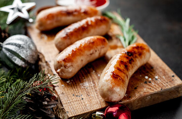 Christmas grilled sausages with spices on a stone background with Christmas trees and Christmas decorations, gifts