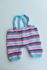 Various colors and types of cotton clothing, knitted newborn clothes and newborn hats on a white background.