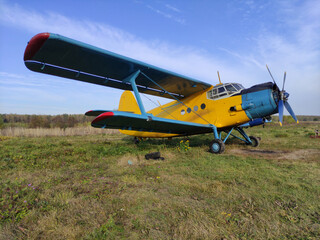 Yellow and blue old biplane plane with a single piston engine and propeller against a blue sky with...