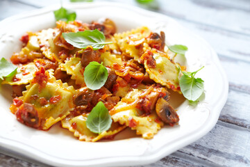 Ravioli with mushrooms and fresh basil. Bright wooden background. Close up. 