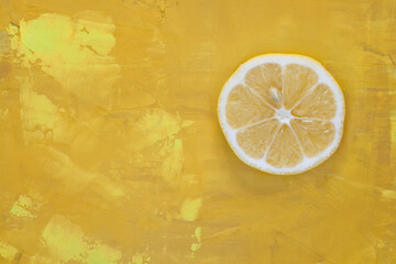 Plaster cytryny na żółtym, namalowanym, abstrakcyjnym tle.