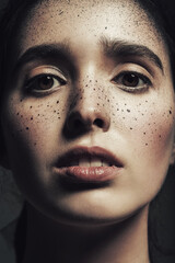 Macro portrait of woman with sprayed black paint on face