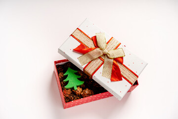 A gift box with cones and a toy Christmas tree stands on a white background