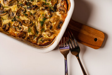 Mushroom julienne in a baking dish stands on a Board on a white background