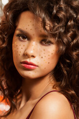 Fototapeta premium Creative winter makeup with golden snowflakes on her face and wavy hairstyle