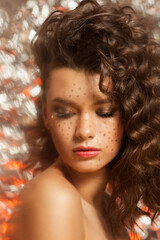 Fototapeta premium Creative winter makeup with golden snowflakes on her face and wavy hairstyle