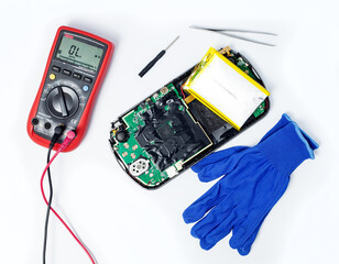 Multimeter, tools, blue gloves and disassembled portable game console on an isolated background....