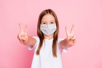 Photo of lovely adorable kid girl make v-sign wear medical mask good look outfit isolated pastel...