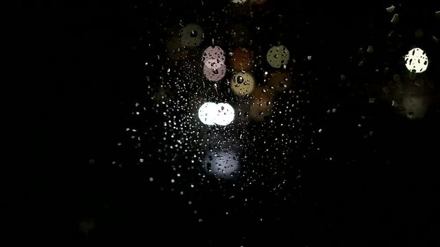Raindrops on the window, view from the window of the house to the street, background. Lantern and car lights, copy space for text, nighttime