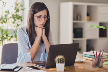 Obraz premium Photo of serious lady fists chin focused face look screen watch screen laptop wear specs shirt in home office indoors