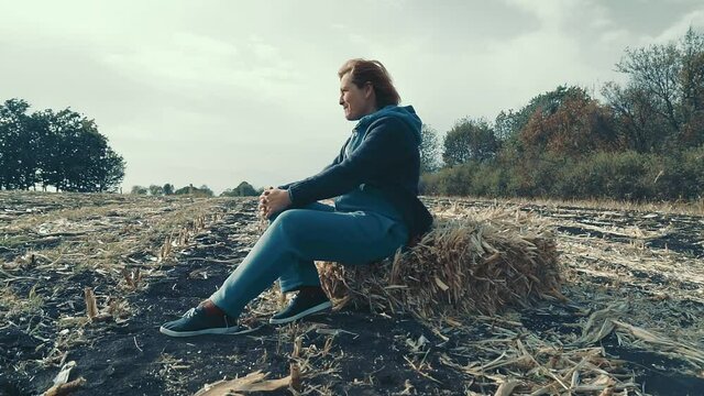 Mature Woman on a haystack. Women farmer sist on a haystack in land.
