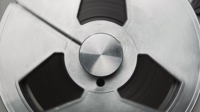 Reel to reel tape recorder playing. Rotating retro tape. Vintage music player close up. Spinning reels metallic color. Party. Loop. Macro. View from above. Popular Disco Trends 60s, 70s, 80s, 90s