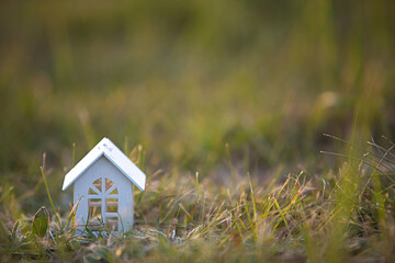 Figures of small white wooden houses on the grass close-up. The cottage is in a rural location and village, building, project, moving , mortgage, rent and purchase real estate. Copy space
