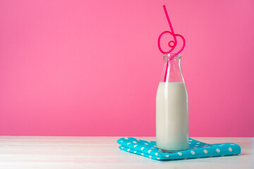 Glass bottle of milk against pink background